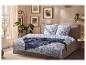 Chambre à coucher avec un lit doté d'une parure de lit à feuilles tropicales bleues et blanches, d'un jeté bleu et d'imprimés botaniques encadrés.