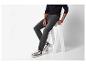 Homme en jean noir et t-shirt à manches longues assis sur un tabouret blanc.