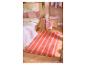 Slaapkamer met citroenprint beddengoed, roze kussens en een gestreepte oranje en roze vloerkleed.