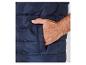 Een donkerblauwe gewatteerde vest met een hand in de zak.