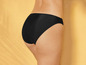 Zwarte string onderbroek op een beige achtergrond.