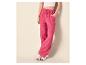 Femme en pantalon large fuchsia et crop top blanc, portant des baskets blanches.