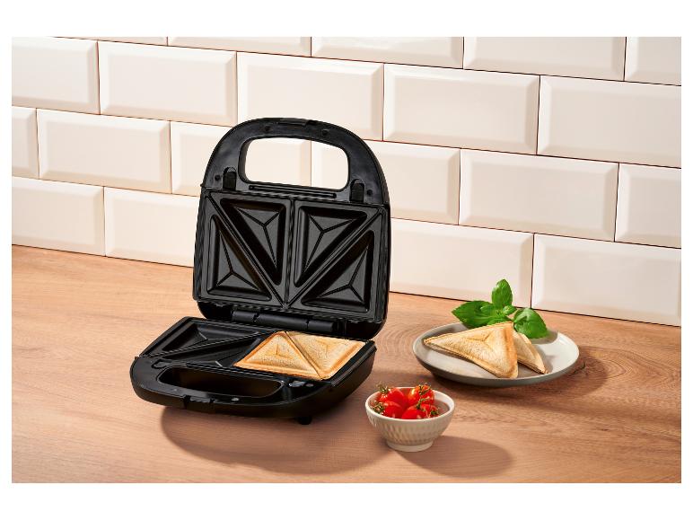 Open tosti-ijzer met kant-en-klare tosti's, tomaten en basilicum.