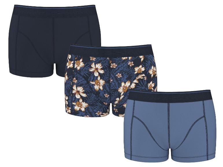 Drie katoenen boxershorts voor heren: één marineblauw, één met bloemenpatroon en één lichtblauw.