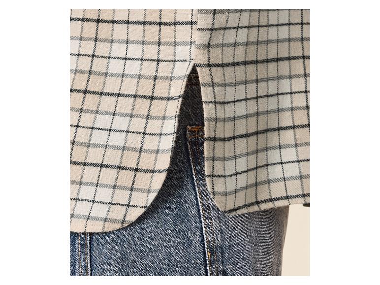 Geruit overhemd in beige en zwarte tinten, gedragen met jeans.