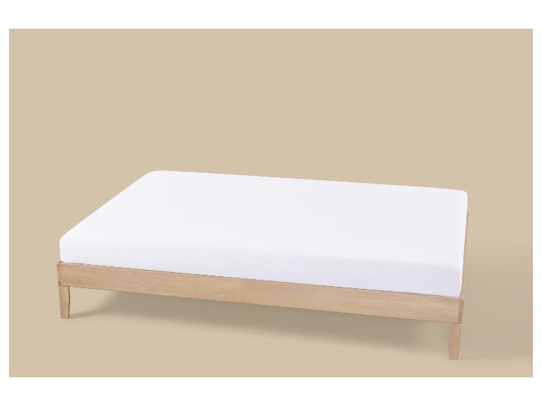 Cadre de lit en bois avec matelas blanc sur fond beige