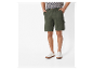 Olijfgroene werkshorts en witte sneakers.