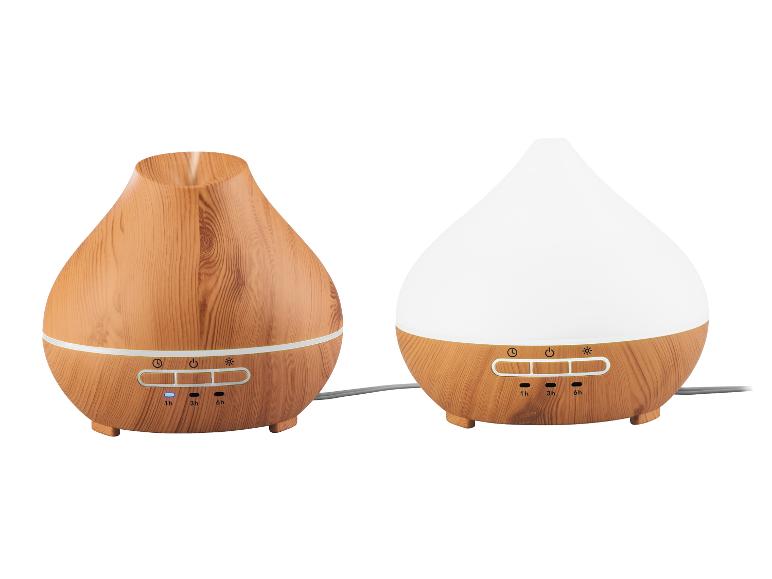Deux diffuseurs d'huiles essentielles en bois clair, l'un avec de la vapeur et l'autre allumé.