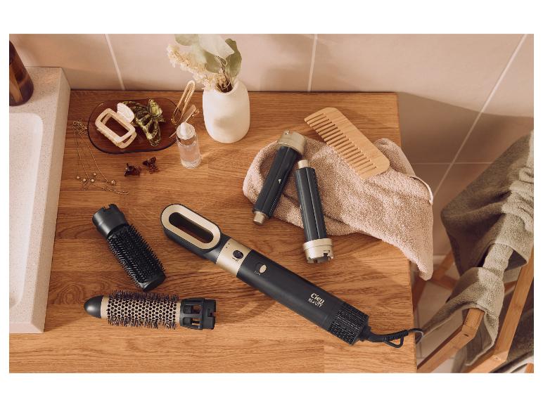 Cien Beauty heteluchtstyler met verwisselbare opzetstukken, haaraccessoires en een houten kam op een badkamerblad.