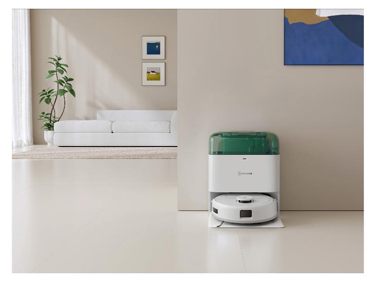Witte robotstofzuiger met groen laadstation in een moderne woonkamer.