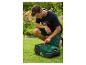 Homme ajustant une tondeuse robot dans le jardin