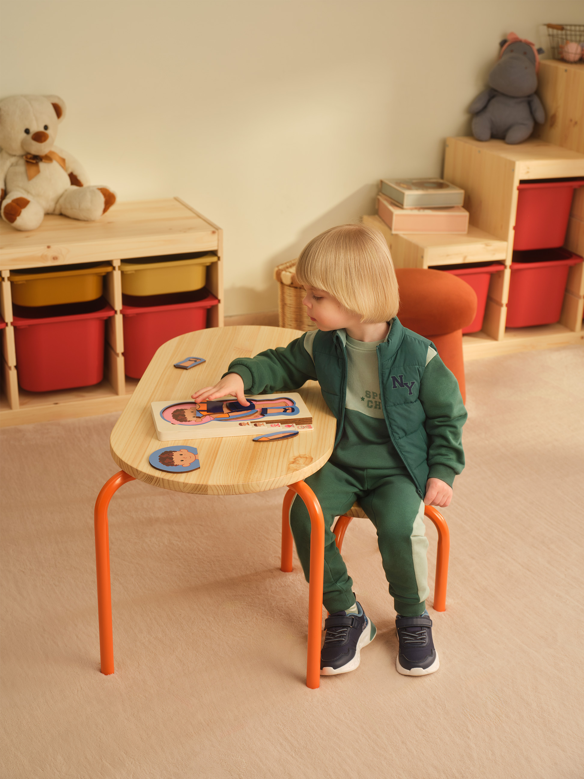 Enfant jouant avec un puzzle en bois à une table d'activités dans une chambre d'enfant.