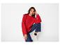 Femme en pull tricoté rouge, jean bleu foncé et baskets blanches épaisses.
