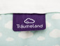 Une étiquette violette avec le texte 'Träumeland' sur une literie bleu clair avec des nuages blancs.