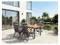 Buiten eethoek met houten tafel en rieten stoelen op een modern terras.