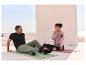 Couple sur tapis de yoga, homme utilise un masseur de pieds, femme un masseur corporel.