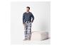 Man in blauw shirt met lange mouwen en geruite pyjamabroek, staand naast een poef.