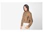 Femme en veste en daim marron et pantalon clair.
