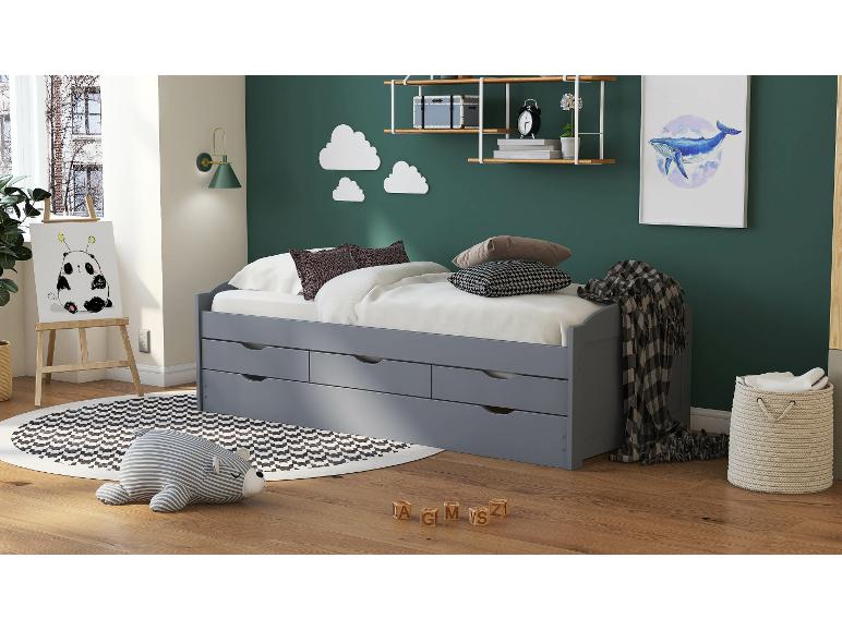 Un lit gris avec trois tiroirs et un tapis rayé dans une chambre d'enfant.