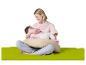 Lachende moeder die haar baby borstvoeding geeft op een voedingskussen, zittend op een groene mat.