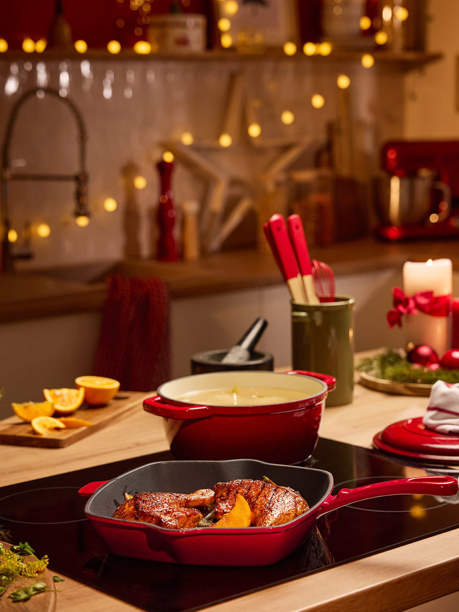 Rode potten en pannen met eten op een kookplaat in een kerstversierde keuken.