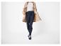 Femme en trench-coat beige, pull blanc et leggings bleu marine avec boutons dorés