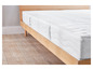 Een wit matras op een houten bedframe.