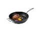 Biefstuk en geroosterde groenten in een zwarte koekenpan met metalen handvat.