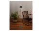 Lampadaire moderne à côté d'une chaise et d'une plante sur une terrasse en bois.