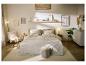 Een gezellige slaapkamer met een bed, nachtkastjes, een stoel en decoratieve elementen in neutrale tinten.