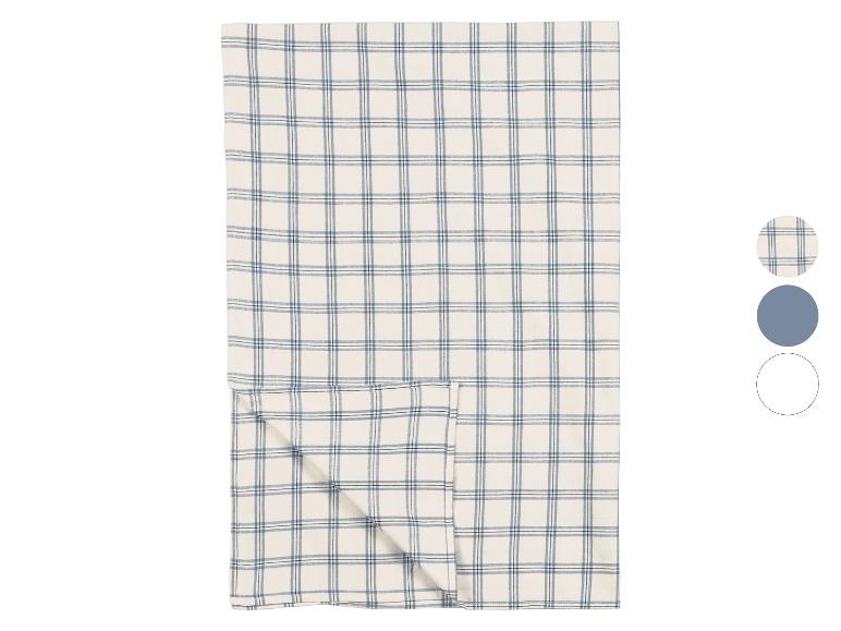 Geruite tafelloper in crèmekleur met blauwe en zwarte lijnen, gevouwen op een witte achtergrond.