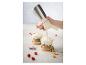 Een hand gebruikt een slagroomspuit om slagroom toe te voegen aan een glas yoghurt met fruit en granola.
