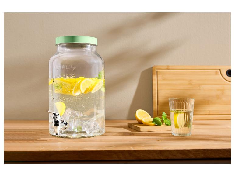 Glazen drankdispenser met citroenen en munt, glas water met citroen op een houten tafel.