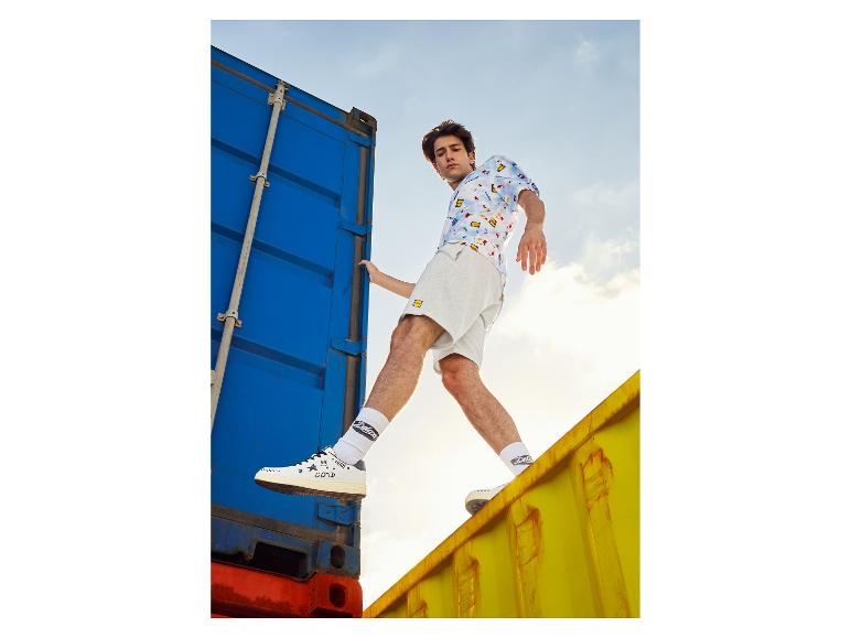 Mannelijk model in short, overhemd met print en Deluxe sneakers.