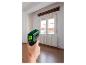 Een hand houdt een Parkside infrarood thermometer vast, die de temperatuur van een raam meet.