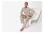 Femme en pyjama beige à motifs floraux, assise sur une chaise blanche.