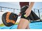Femme sur un court de padel avec une raquette de padel noire et une balle de tennis dans sa poche.