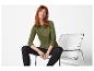 Femme en haut à manches longues vert olive et leggings noirs assise sur une chaise.