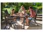 Familie geniet van een buitenmaaltijd met een tuintafel en stoelen.
