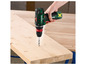 Een groene Parkside schroevendraaier boort in een houten plank.