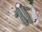 Een groene en roze winteroverall met capuchon op een houten vloer met sneeuw.