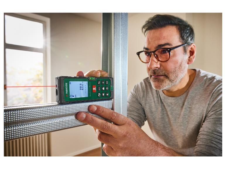 Een man gebruikt een Parkside laser afstandmeter om een metalen frame te meten.