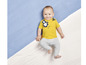 Un bébé portant un t-shirt jaune avec un motif de singes et un legging gris.