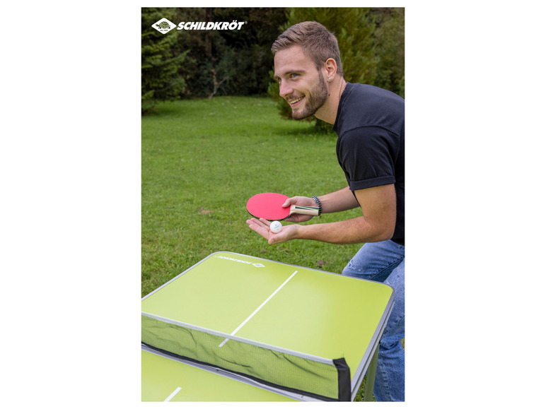 Een man speelt tafeltennis op een Schildkröt tafel buiten.