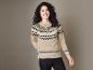 Femme portant un pull beige à motif scandinave et un pantalon noir.