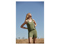 Een vrouw draagt een groene jumpsuit in een veld.