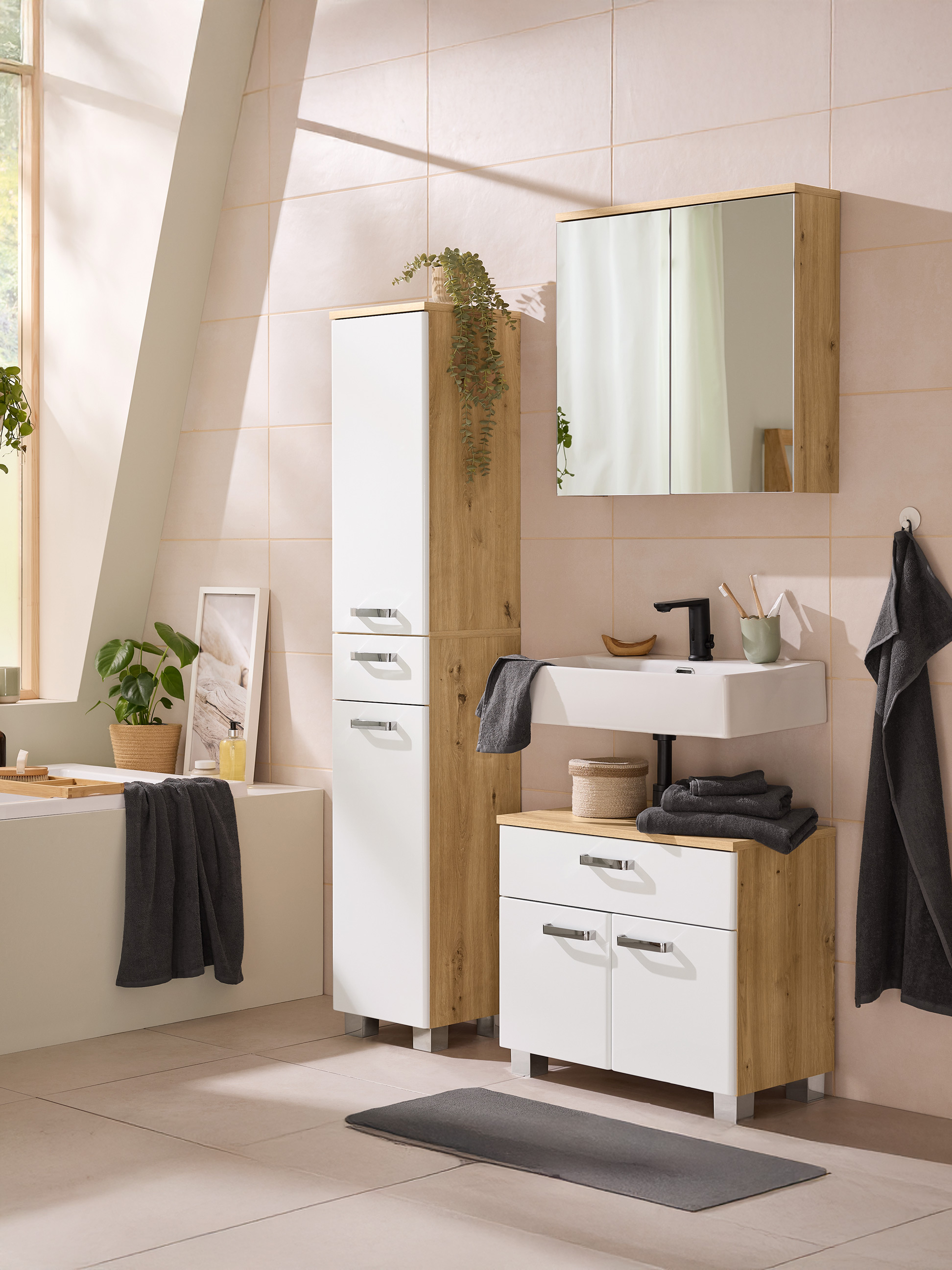 Moderne badkamer met licht houten en witte meubels, wastafel, spiegel en grijze handdoeken.