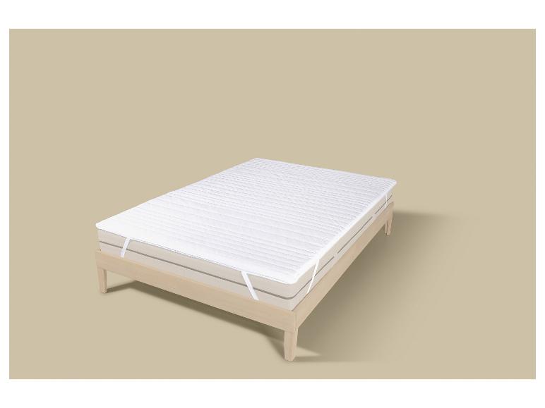 Matras met witte matrasbeschermer op een houten bedframe