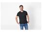 Man in zwart T-shirt en blauwe jeans, lachend tegen een witte achtergrond.