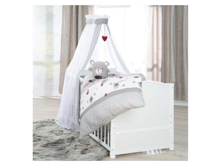 Lit bébé blanc avec ciel de lit, parure de lit à carreaux gris et ours en peluche.
